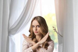tende bianche sullo sfondo e donna che fa segno no