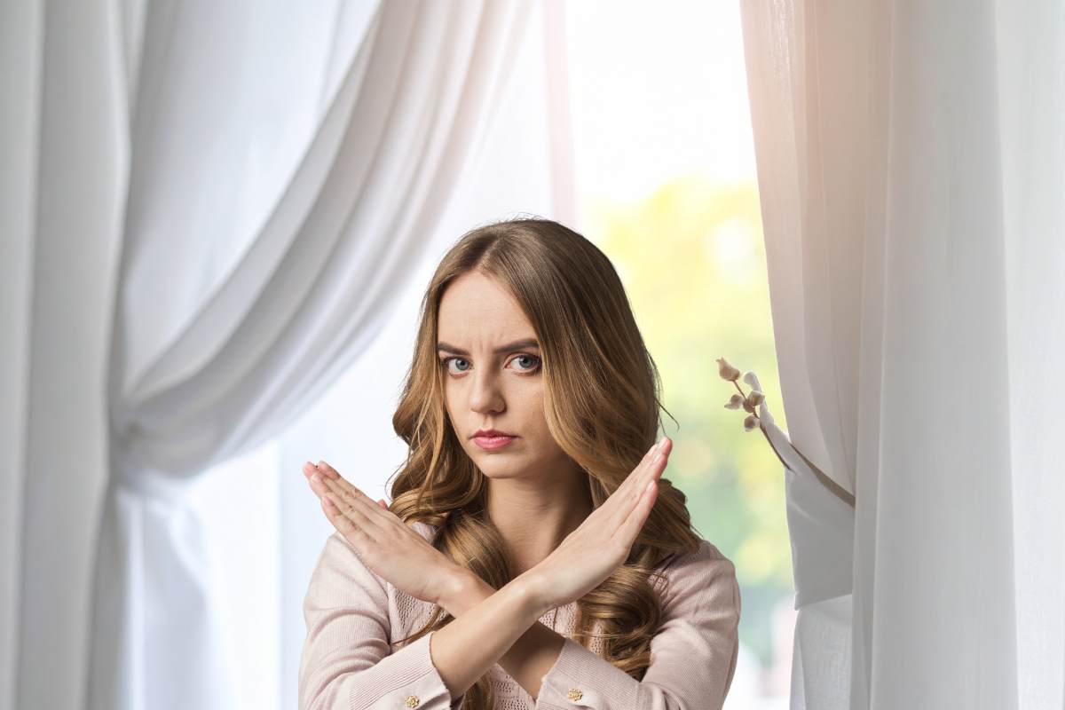 tende bianche sullo sfondo e donna che fa segno no