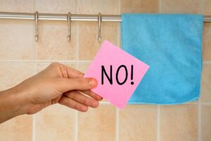 strofinaccio appeso in cucina e mano che mantiene un post-it con scritto no