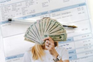 sfondo di una busta paga e donna che mantiene dei soldi in primo piano