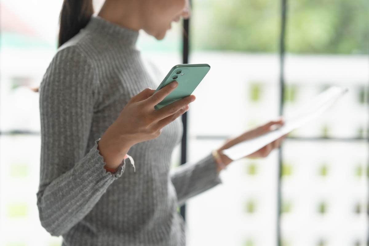 donna con cellulare e foglio in mano