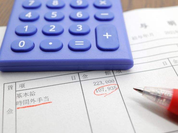 busta paga, calcolatrice e penna rossa