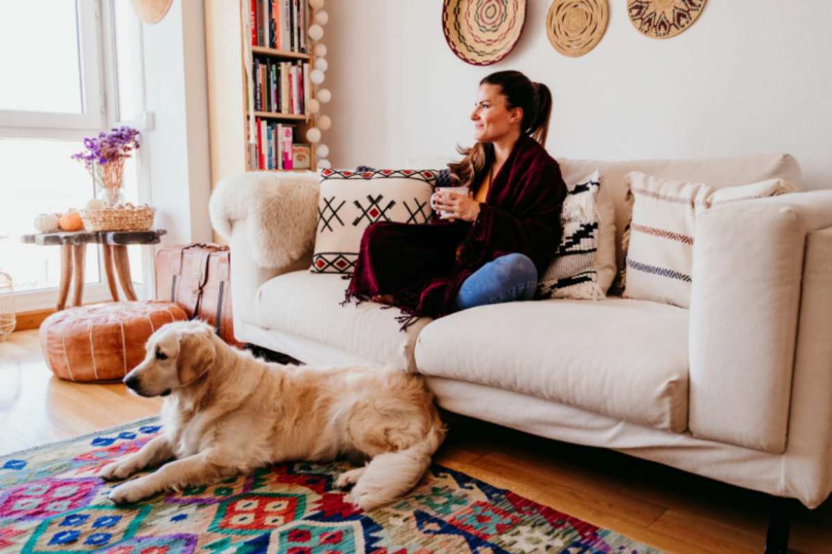 donna sul divano con in mano una tazza e cane sul tappeto