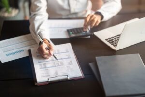 persona con fogli e calcolatrice su di un tavolo