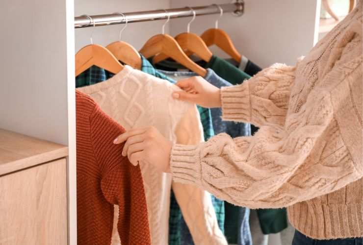 donna che sceglie indumenti pesanti dal suo armadio 