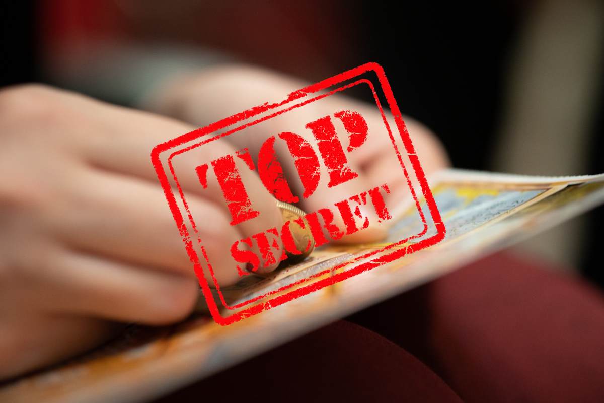 mano che gratta biglietto e scritta top secret