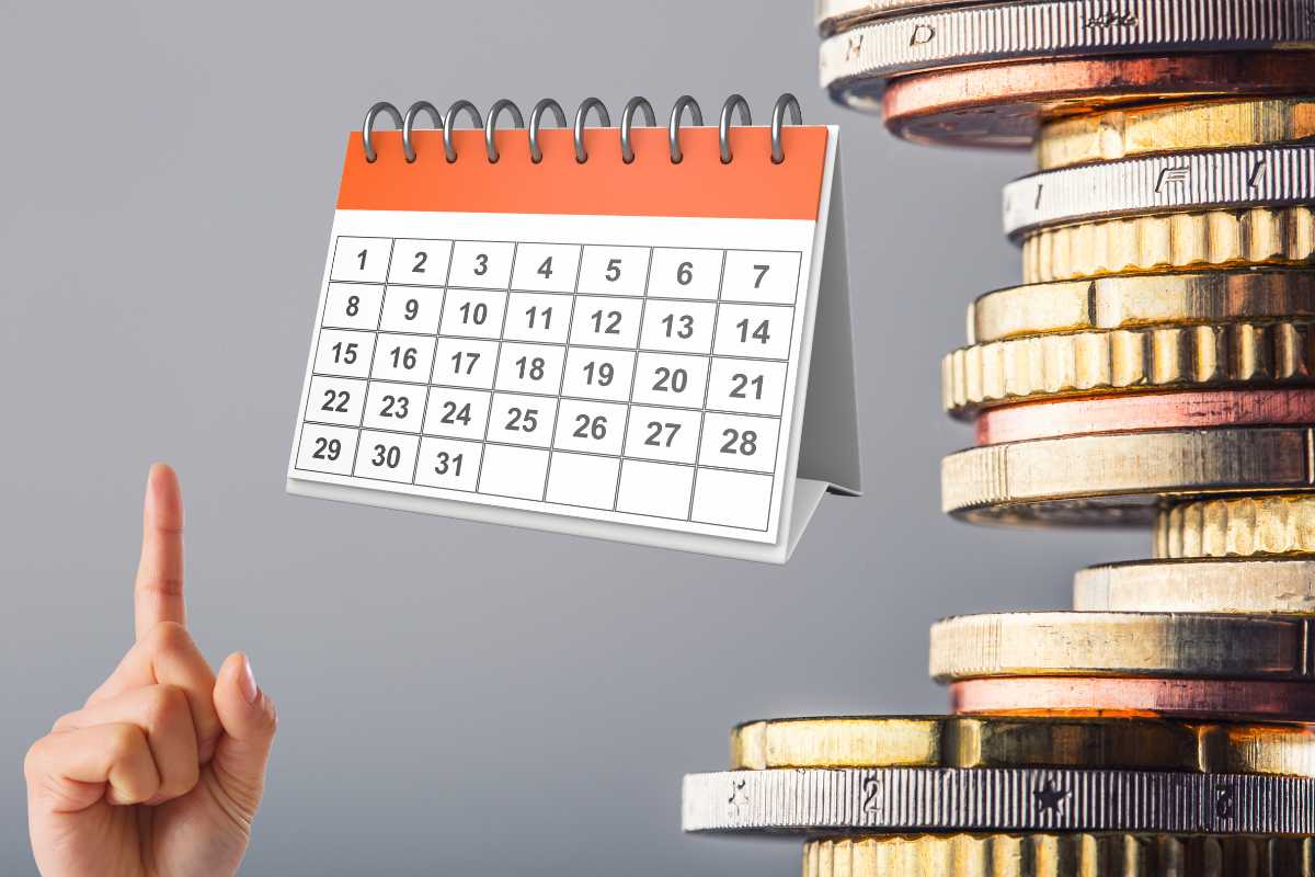 Soldi in bilico con vicino un calendario da tavolino ed un calendario che lo indica