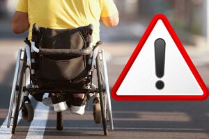 persona in carrozzina e simbolo attenzione