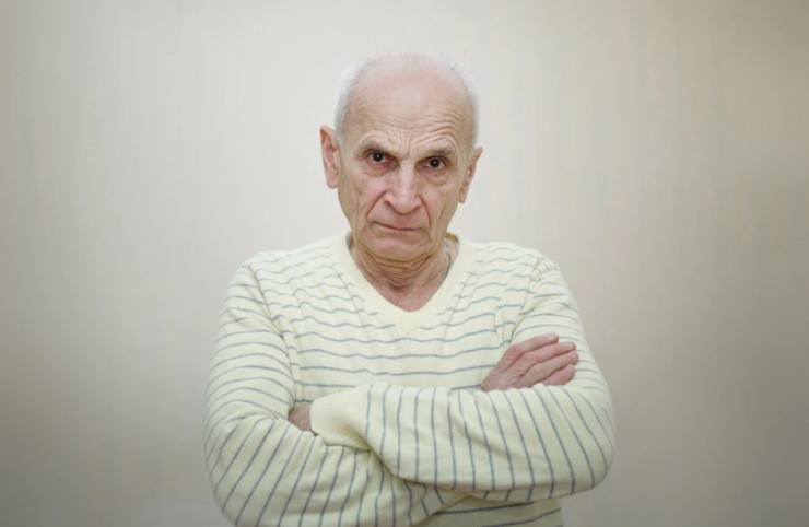 uomo anziano con le braccia incrociate e l'espressione arrabbiata