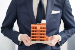 uomo con in mano un condominio in miniatura
