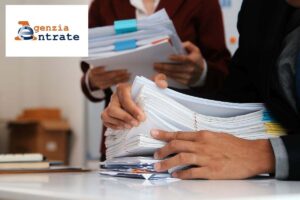 uomo e donna verificano documenti fiscali e logo agenzia delle entrate