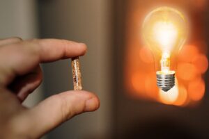 mano con pellet e sullo sfondo stufa accesa con lampadina