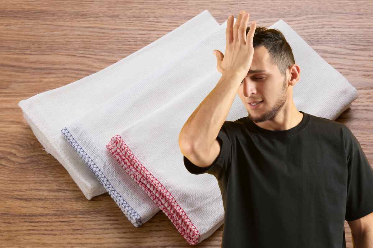 strofinacci bianchi e uomo con mano sul volto 